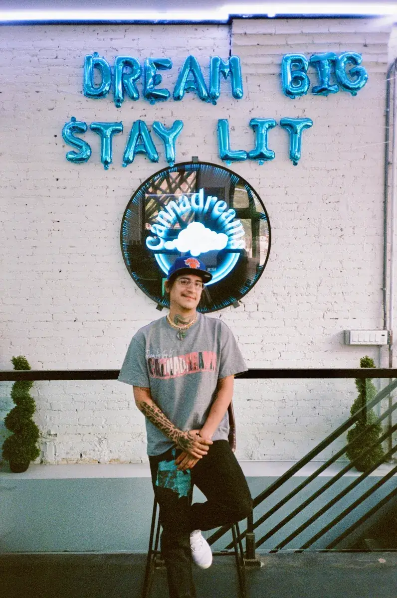 Cannadreams team member in front of the neon Cannadreams sign