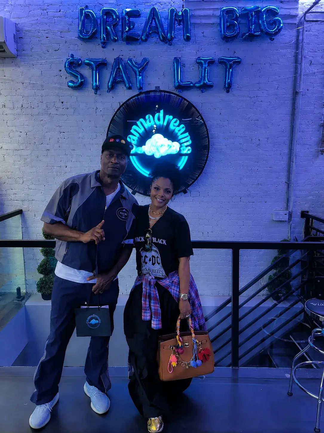 Rasheeda and Kirk Frost from Love & Hip Hop posing in front of the Cannadreams neon sign inside the Hell's Kitchen dispensary