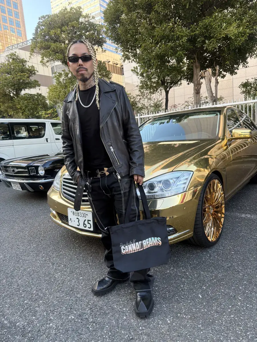 Cannadreams tote bag held next to a gold-plated luxury car in Tokyo, Japan