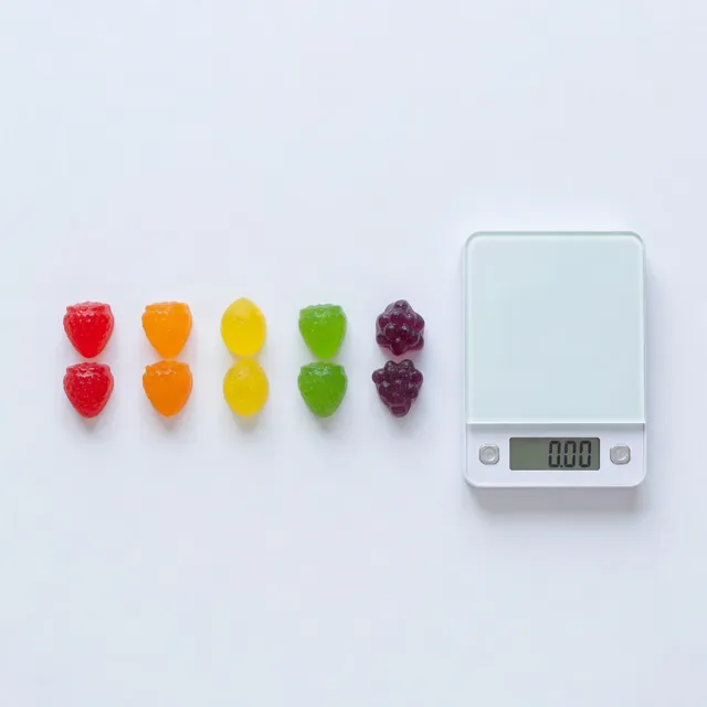 Cannabis gummies lined up beside a scale for edibles dosing