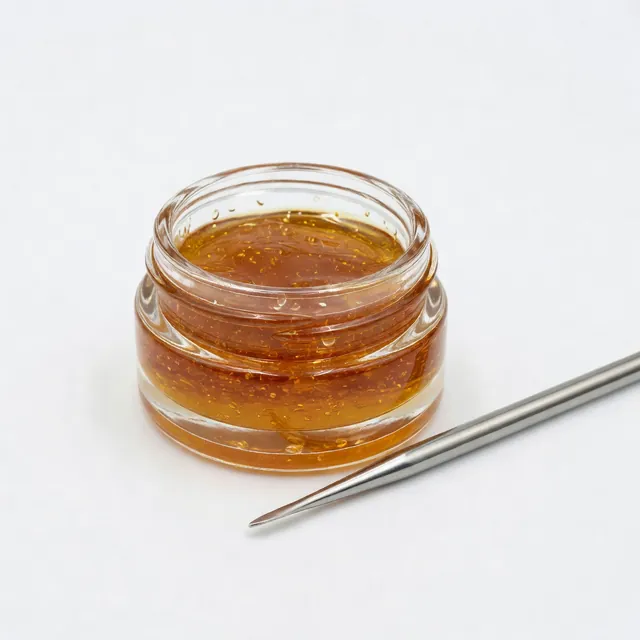 Jar of golden cannabis live resin concentrate with a dab tool